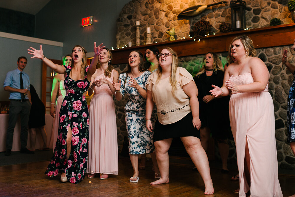 bride tosses bouquet to excited women at the reception 