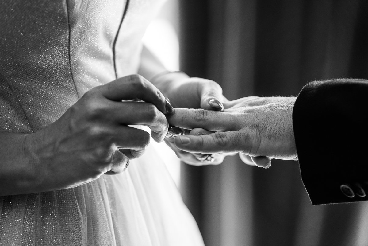 Black and white Engagement picture of couple exchanging rings.