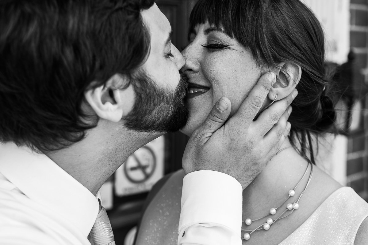 Black and white image of couple kissing on wedding day.