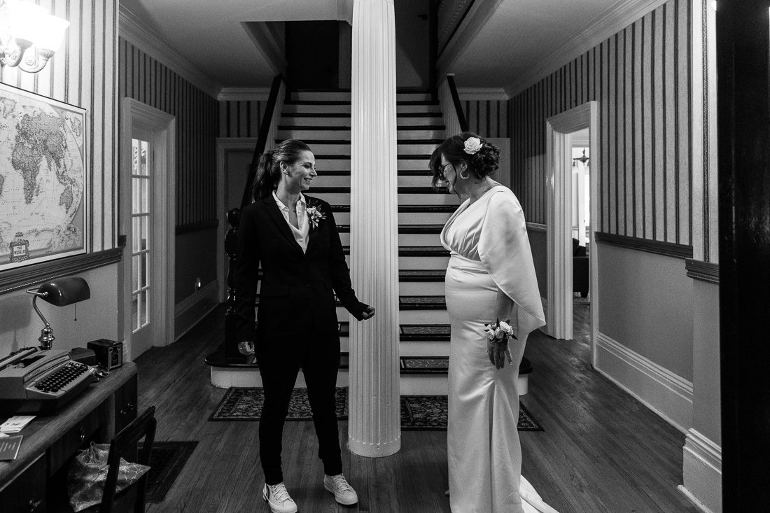 Black and white image of brides looking at each other in the hotel lobby.