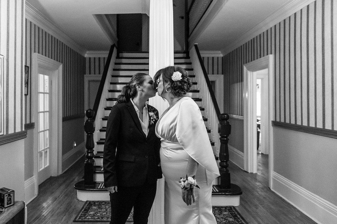 Black and white image of brides kissing each other.
