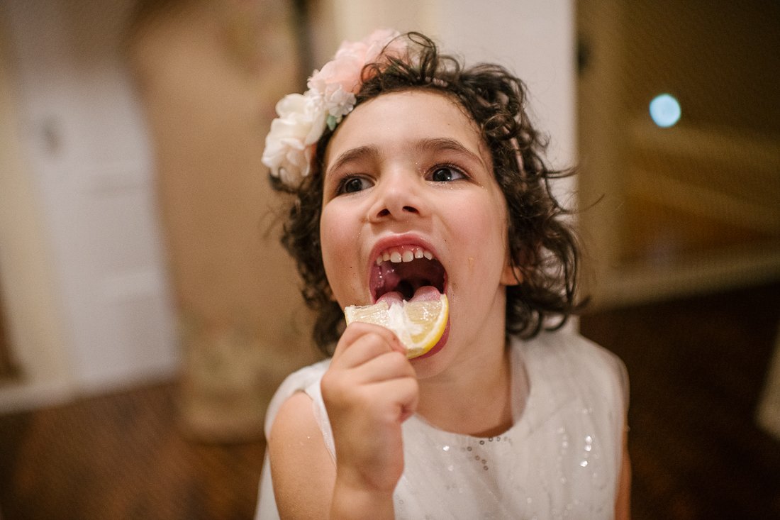 Cute little girl eating orange during wedding party