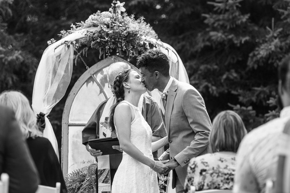 Black and white picture of Bride and groom holding each other hands kissing after wedding. 