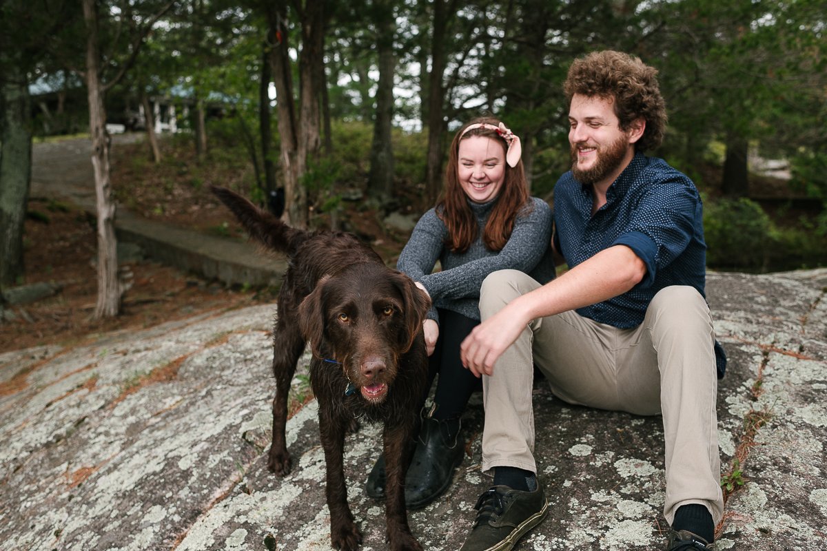 Beautiful couple with their brown dog sitting at the rock