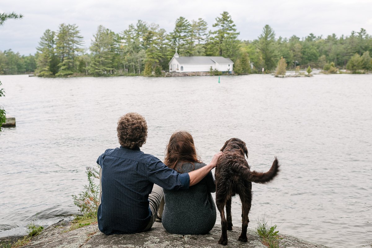 Couple with brown dog sitting near lake