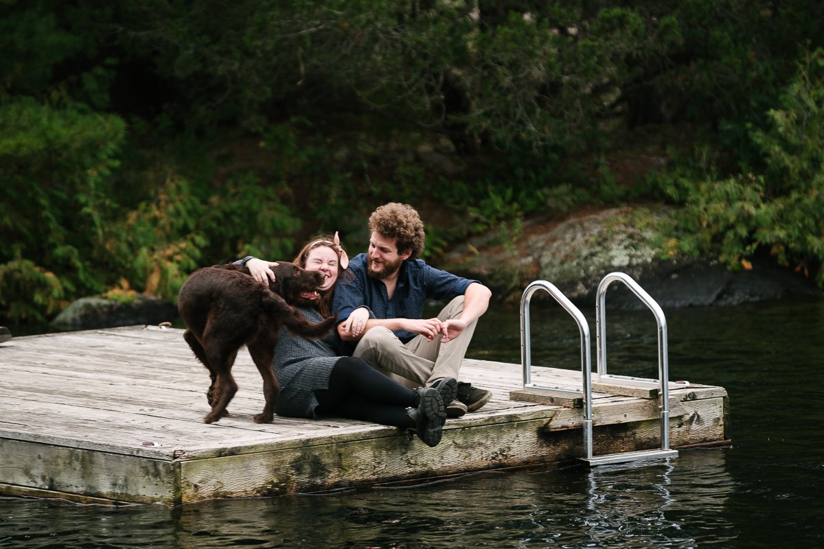 Couple sitting near stony lake with their dog