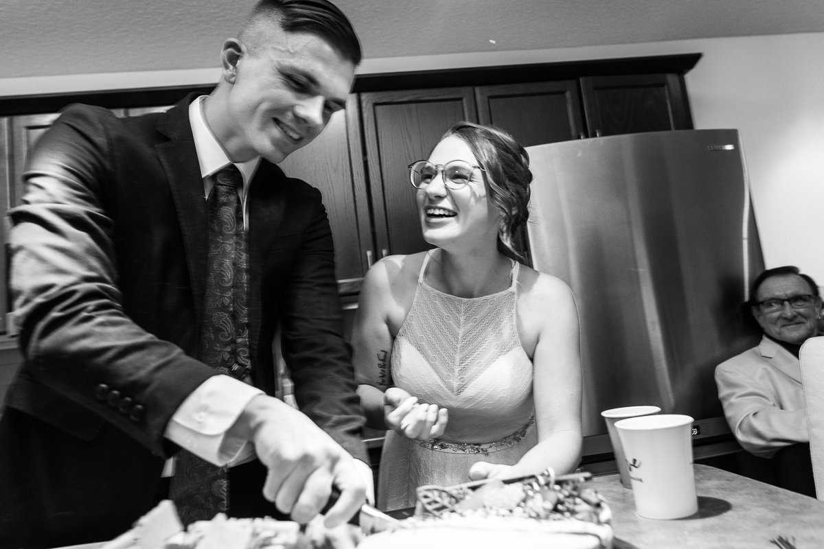 Black and white image of Bride and groom cutting cake after the wedding. 