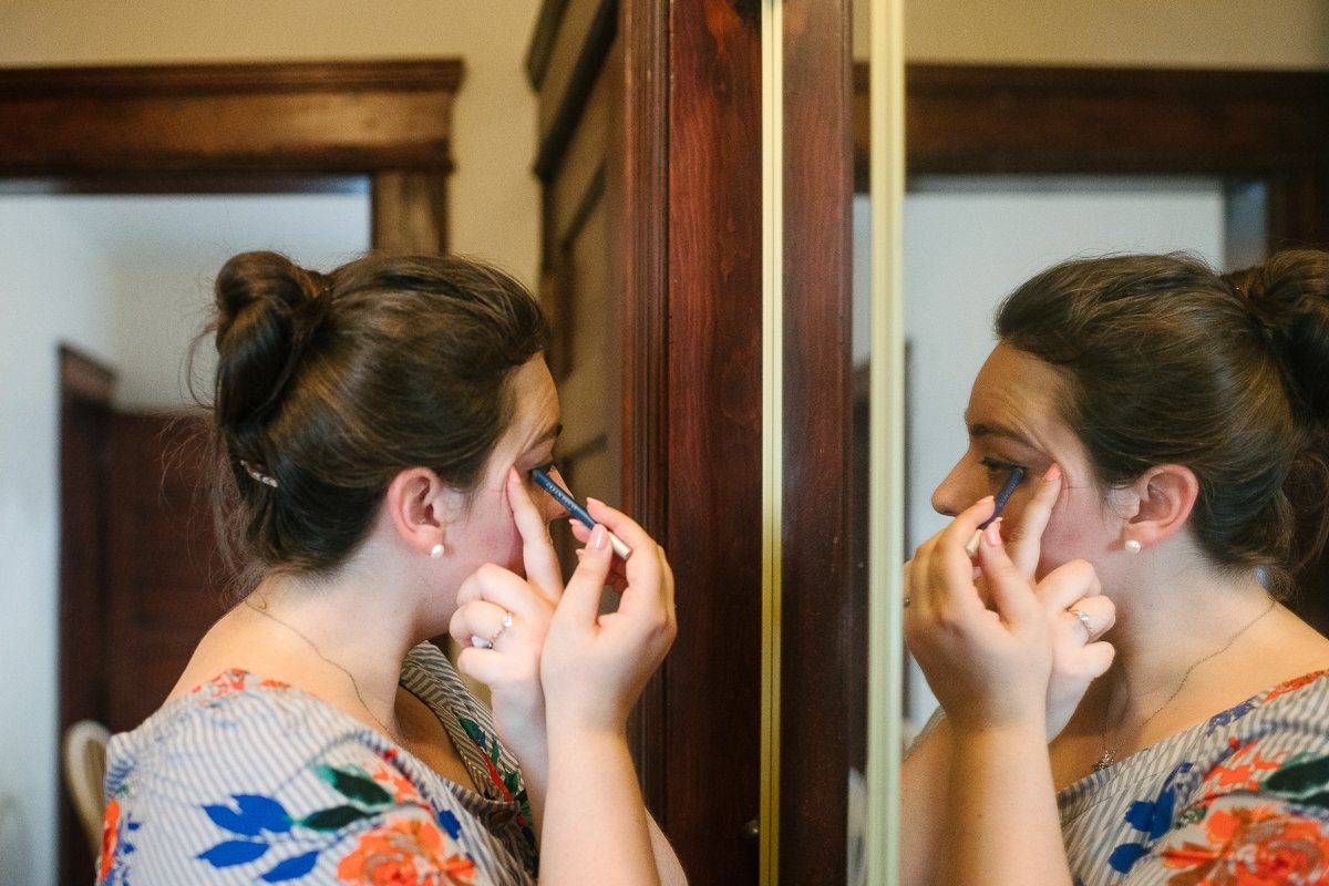 Girl applying eyeliners looking into the mirror