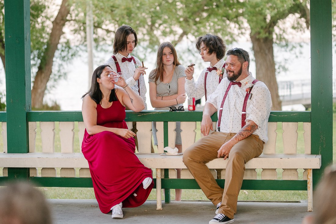 Newly wedded couple and their kids enjoying their day sitting at the bench