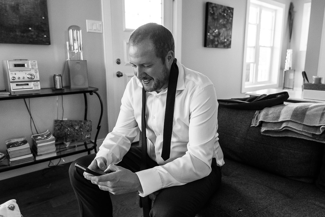 Black and white image of groom getting ready in the room