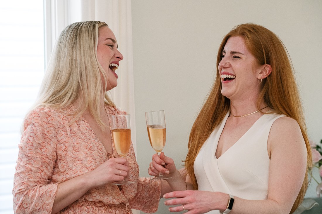 Bride and her sister smiling with happiness holding drinks
