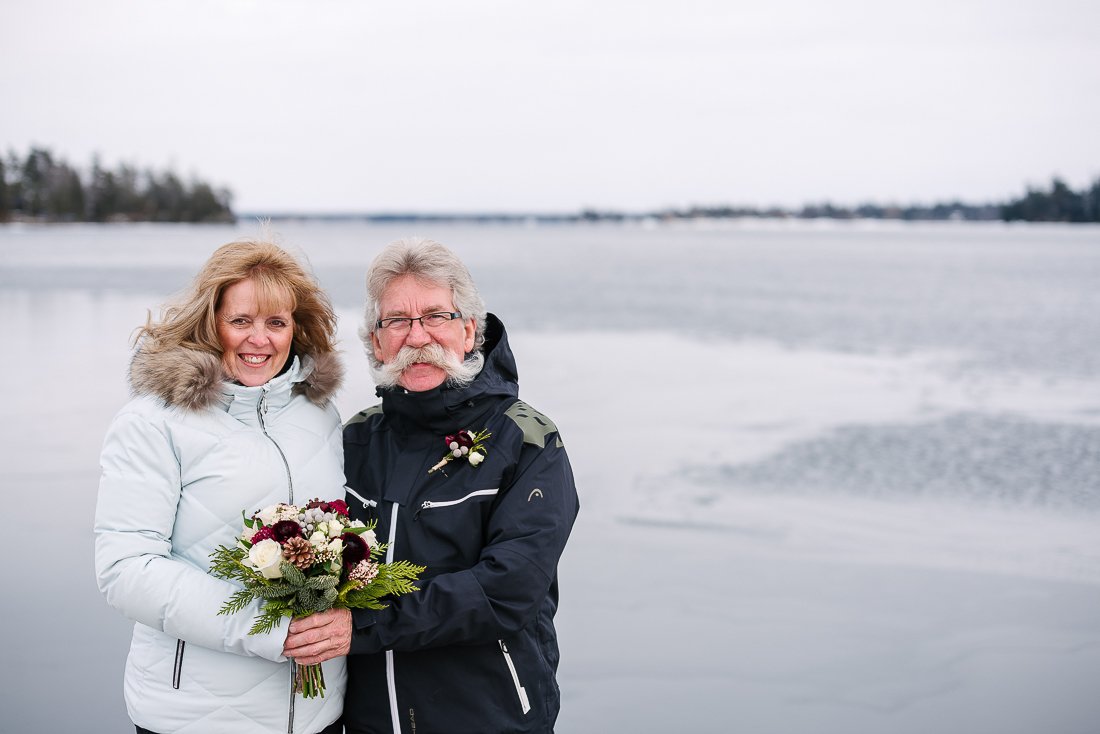 Bride and groom holding bouquet near the lake