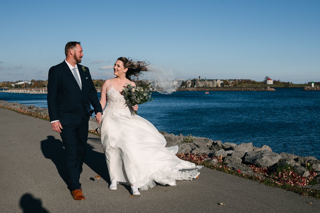 Bride and groom walking near the sea holding wedding bouquet