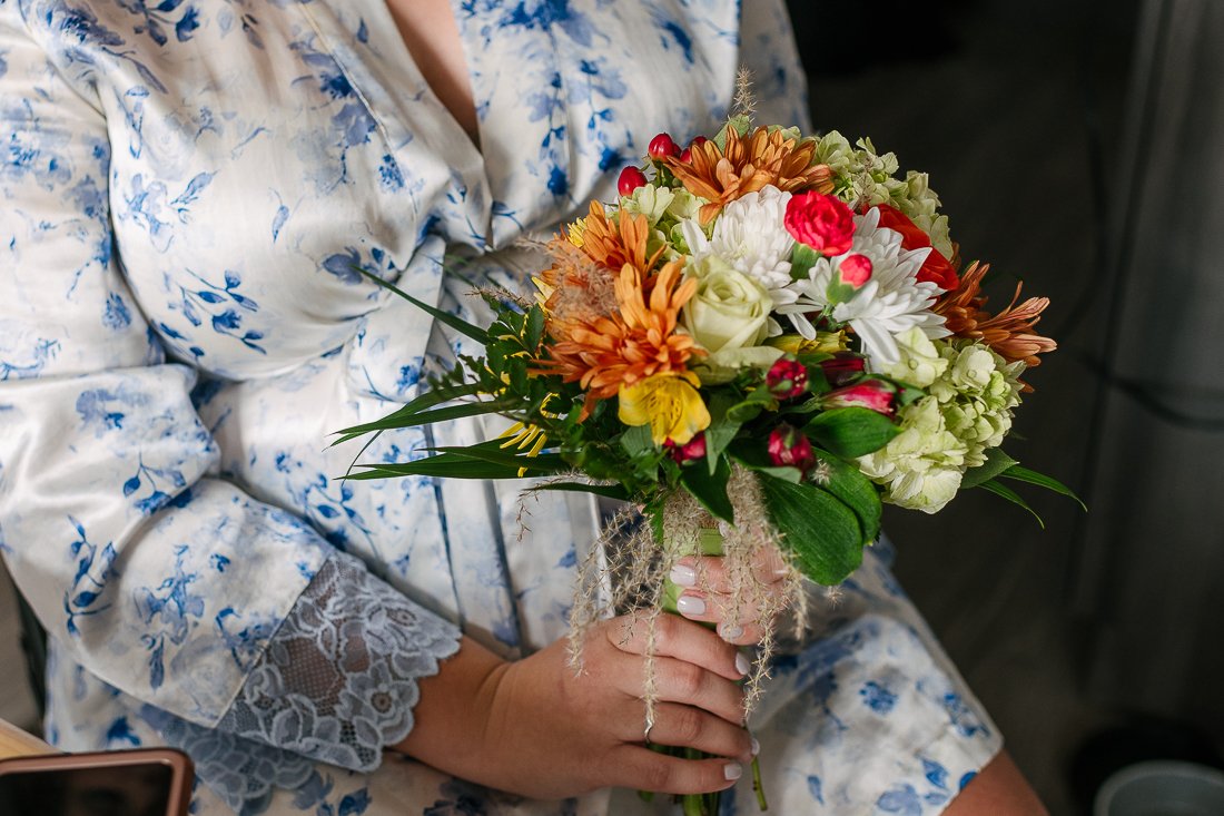 Bride holding flower bouquet wearing white and blue dress
