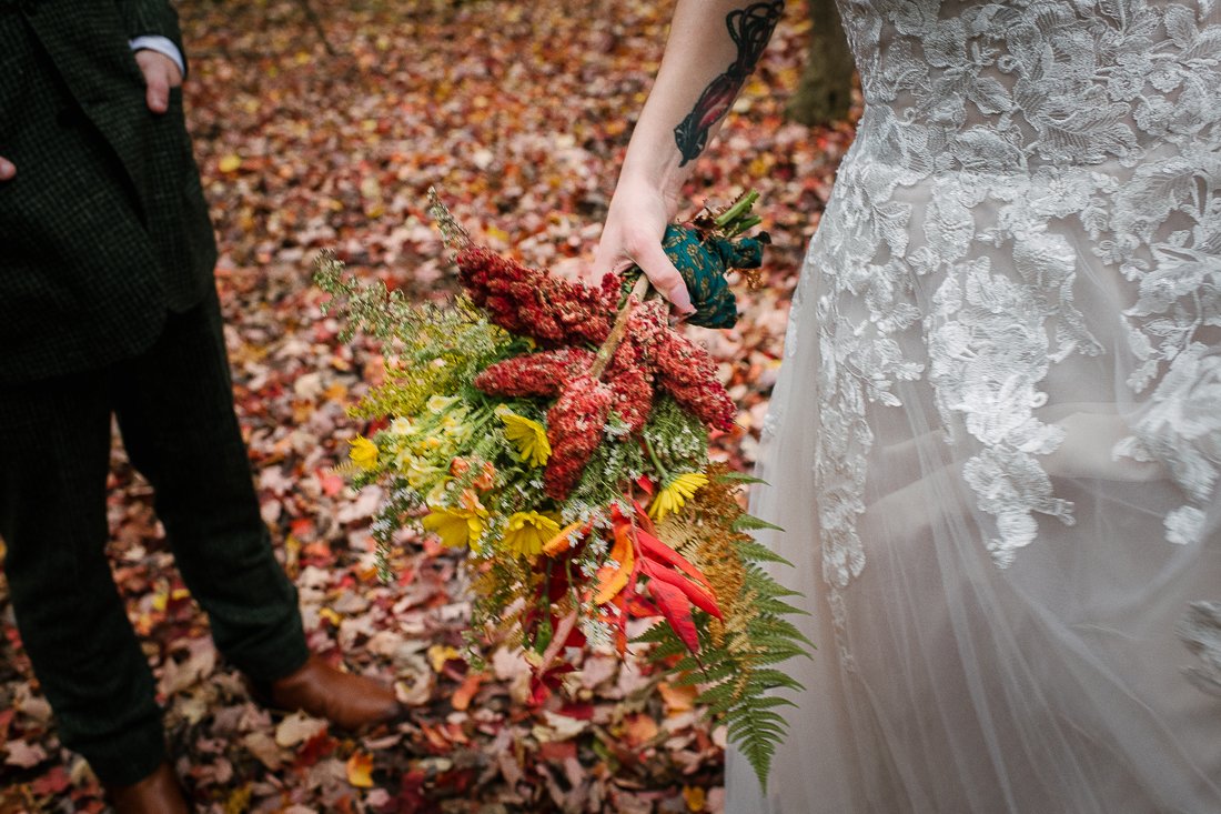 Bride running on the dried leaves holding wedding bouquet