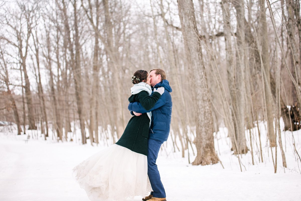 Bride and groom kissing in the snowy forest