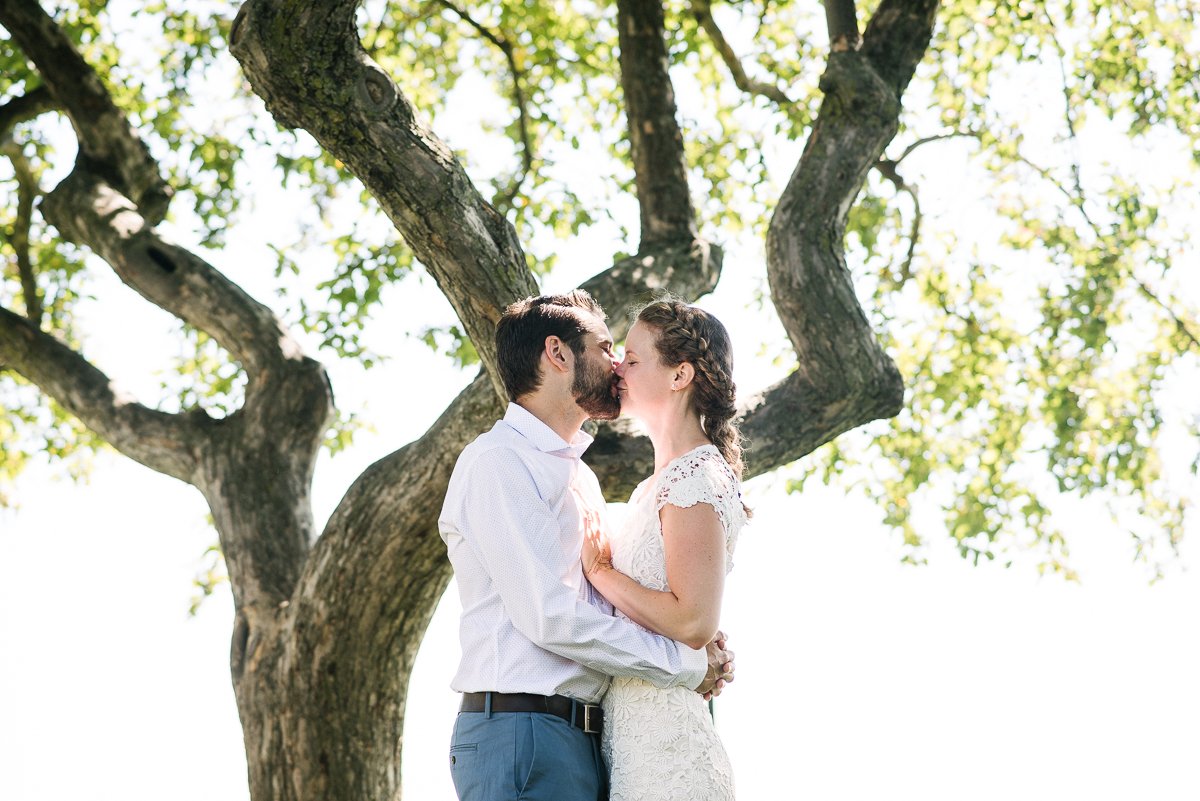 Bride and groom kissing near the tree