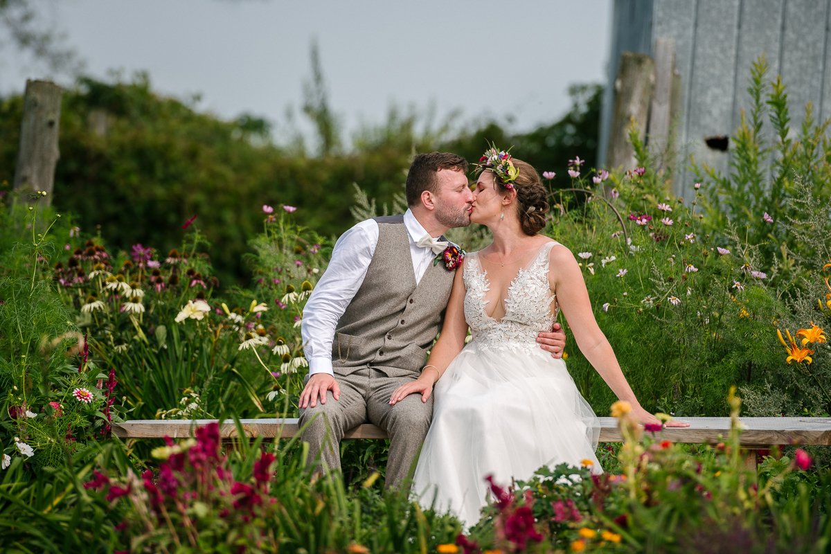 Bride and groom kissing sitting in the garden