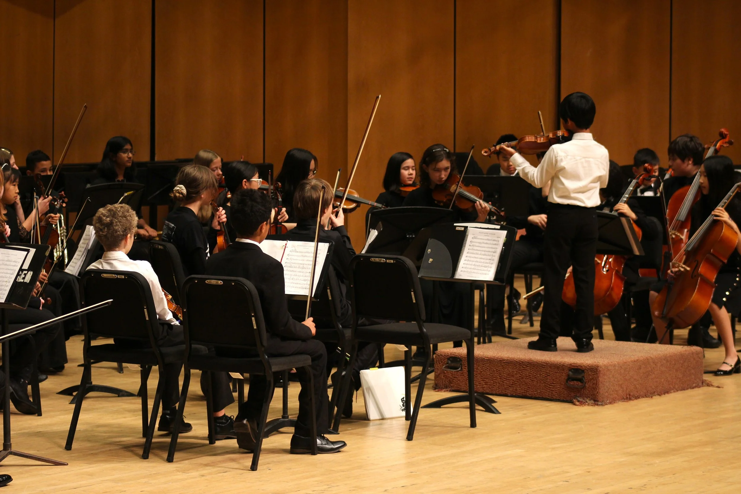 a young concert master tunes his violin with his young orchestra