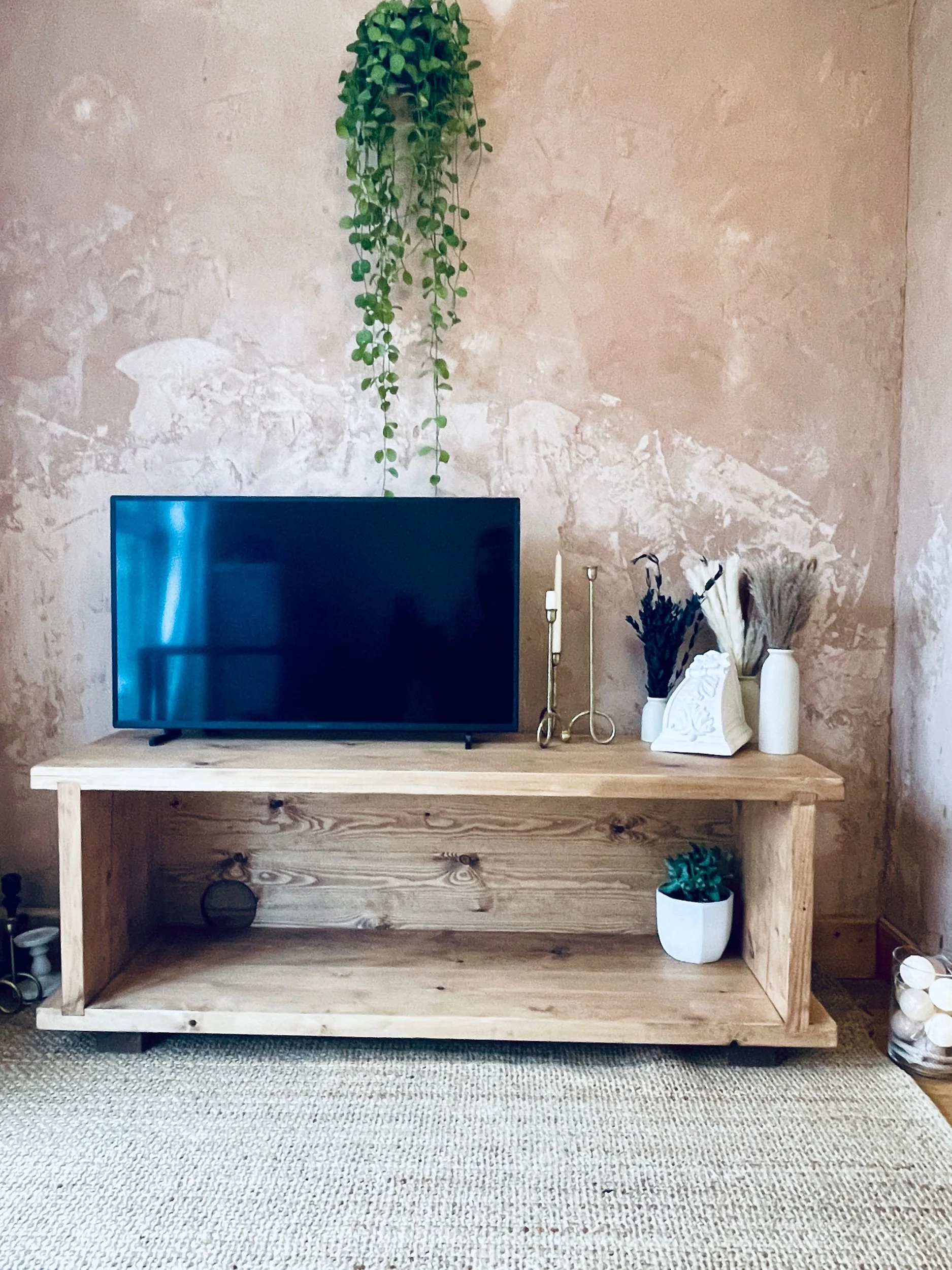 Solid wood media unit used as TV stand with open shelf, AV stack on left and decorative vases on right