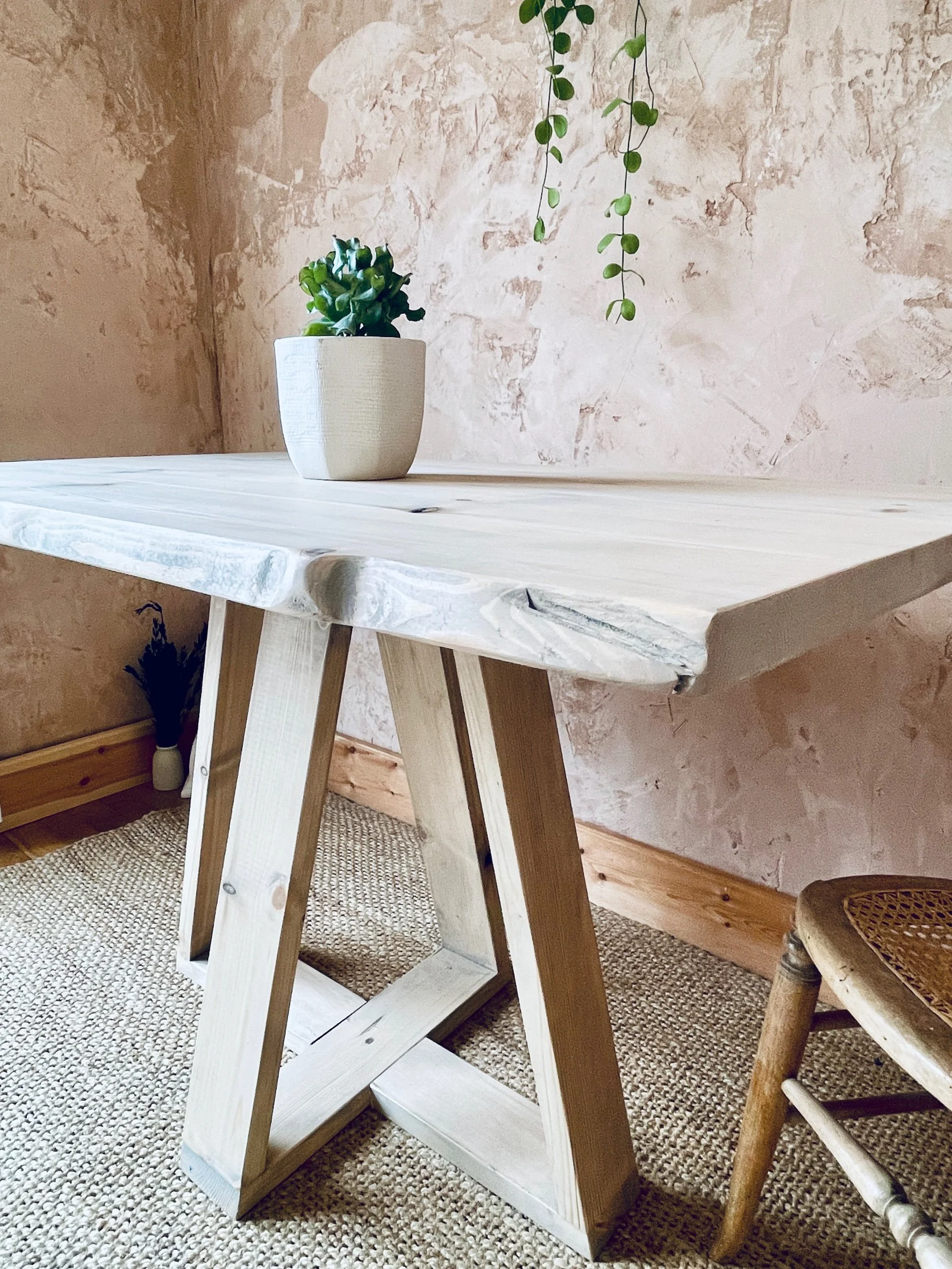 Close-up of light solid-wood dining table corner showing tapered legs and natural grain