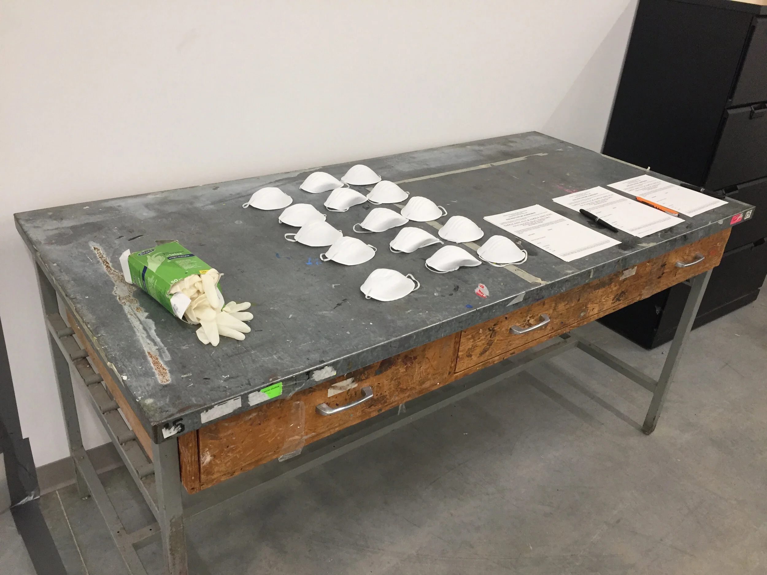 Michael Edward Miller Critical Space Item , 2018, dyed slip cast fired clay powder, laser cut coloured plexiglass, plastic catering container, authentic NASA critical space item label, altered authentic NASA non-disclosure agreements, respiratory masks, hypoallergenic gloves, stainless steel tables, plastic quarantine sheets, actors, participants