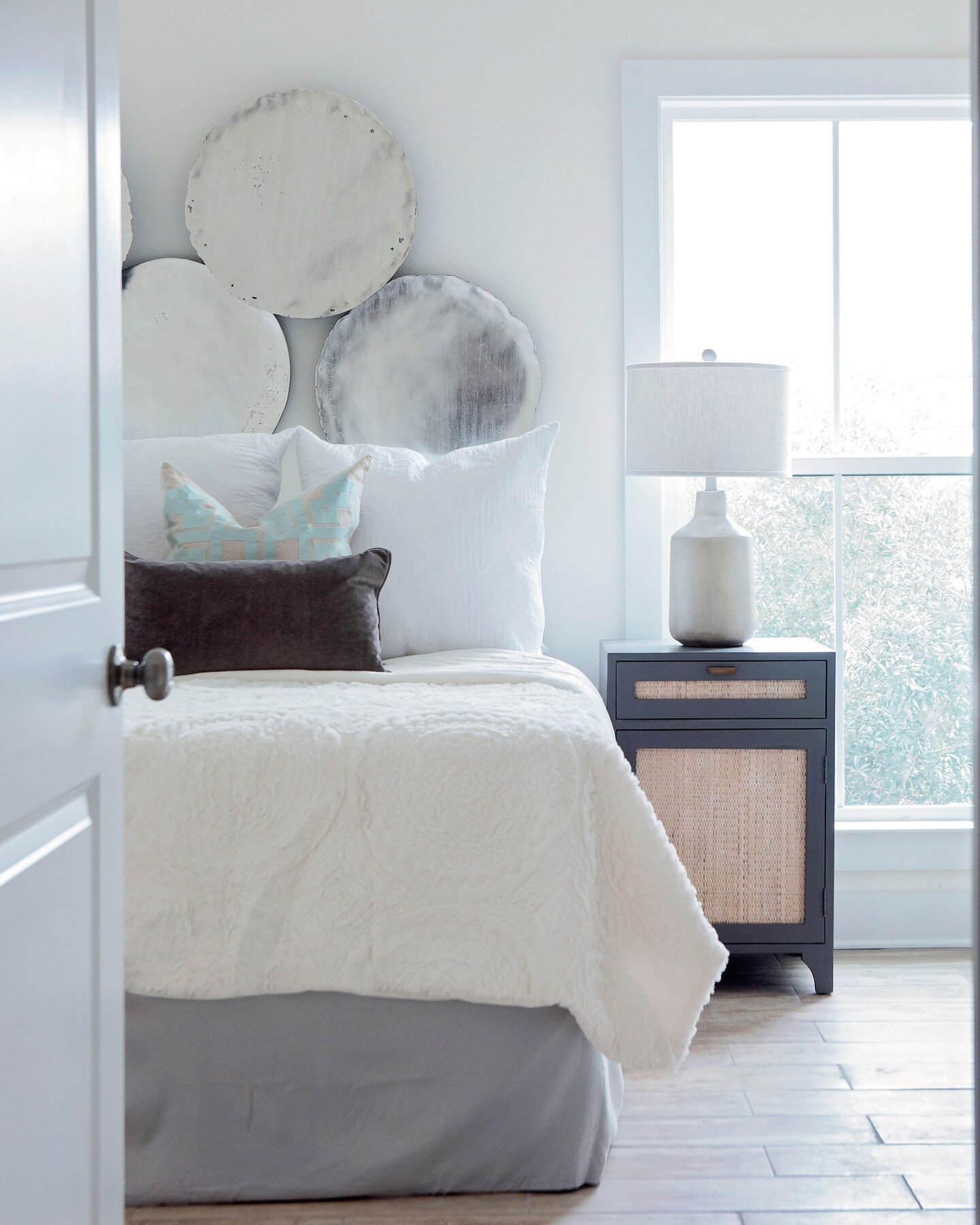 Wall decor can sometimes be tricky to figure out, especially behind a bed with a shorter headboard. In this bedroom we pretty much made our own &quot;headboard&quot; with these silver disks. They add a unique texture and also reflect light to help th