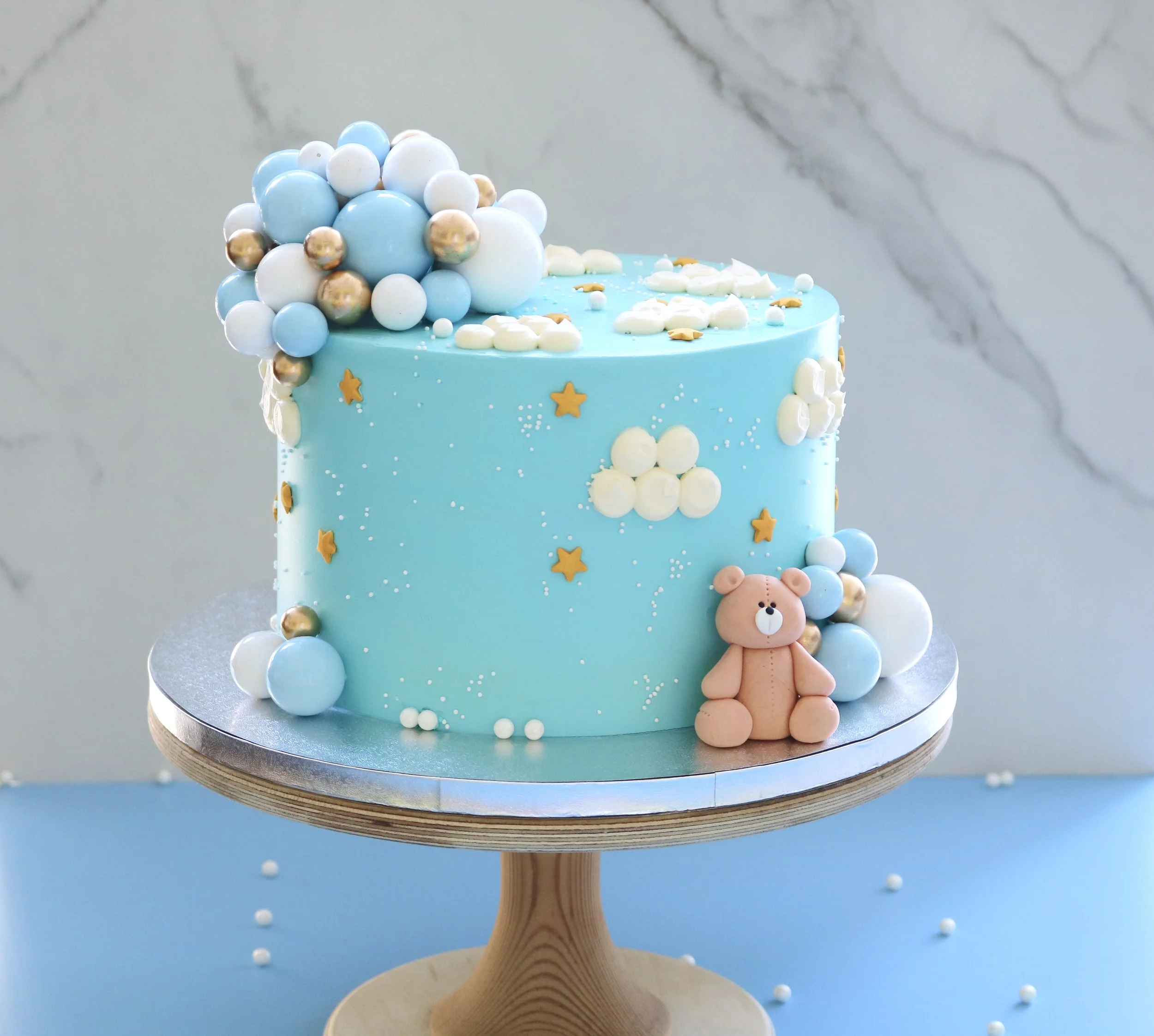 Blue teddy bear cake with balloons, clouds, gold stars and pearl sprinkles