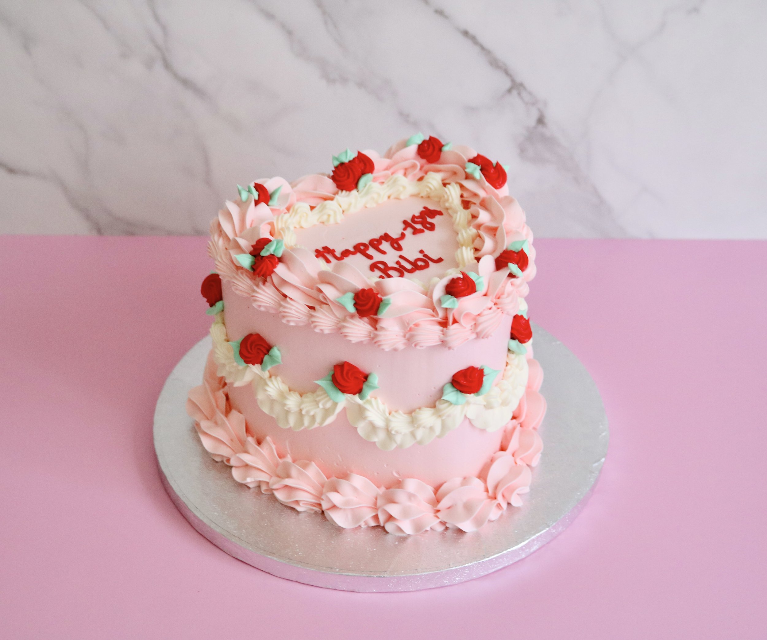 vintage heart cake in light pastel pink with red roses, vintage piping on the side and green