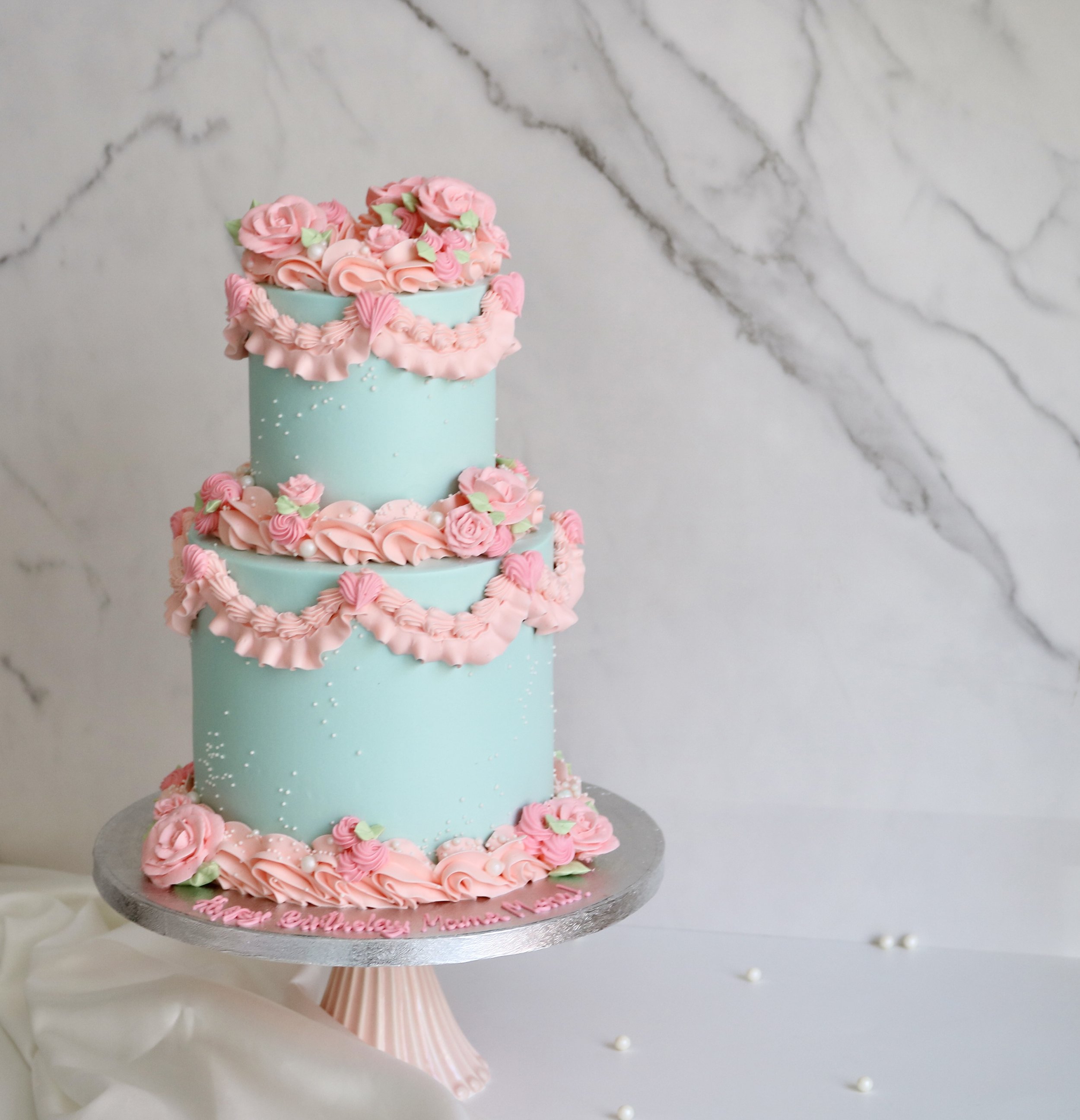 2 tiered vintage cake with blue and pink piping and buttercream roses for all occasions
