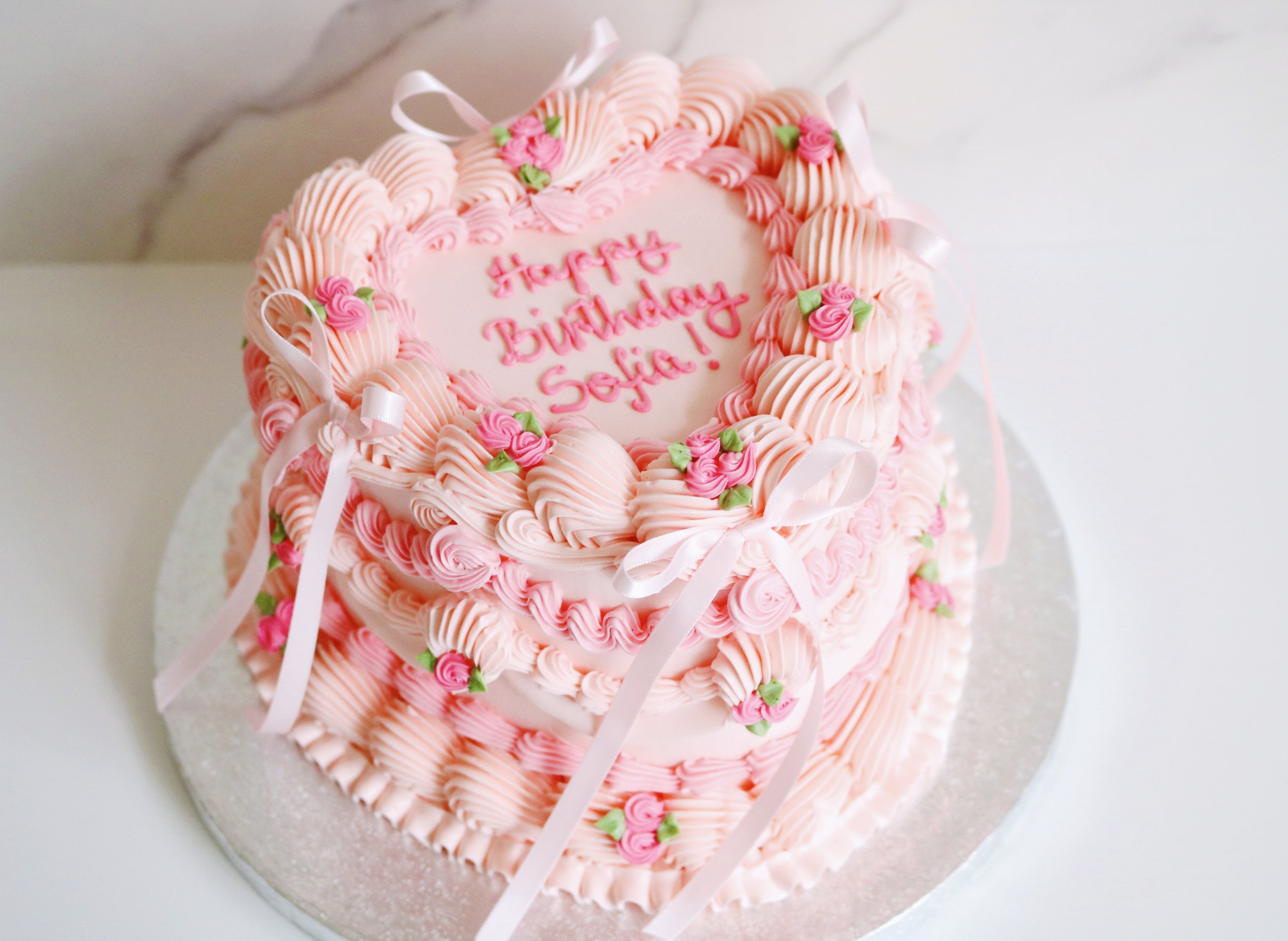 heart-shaped cake in vintage style, decorated in pink theme with roses and ribbons