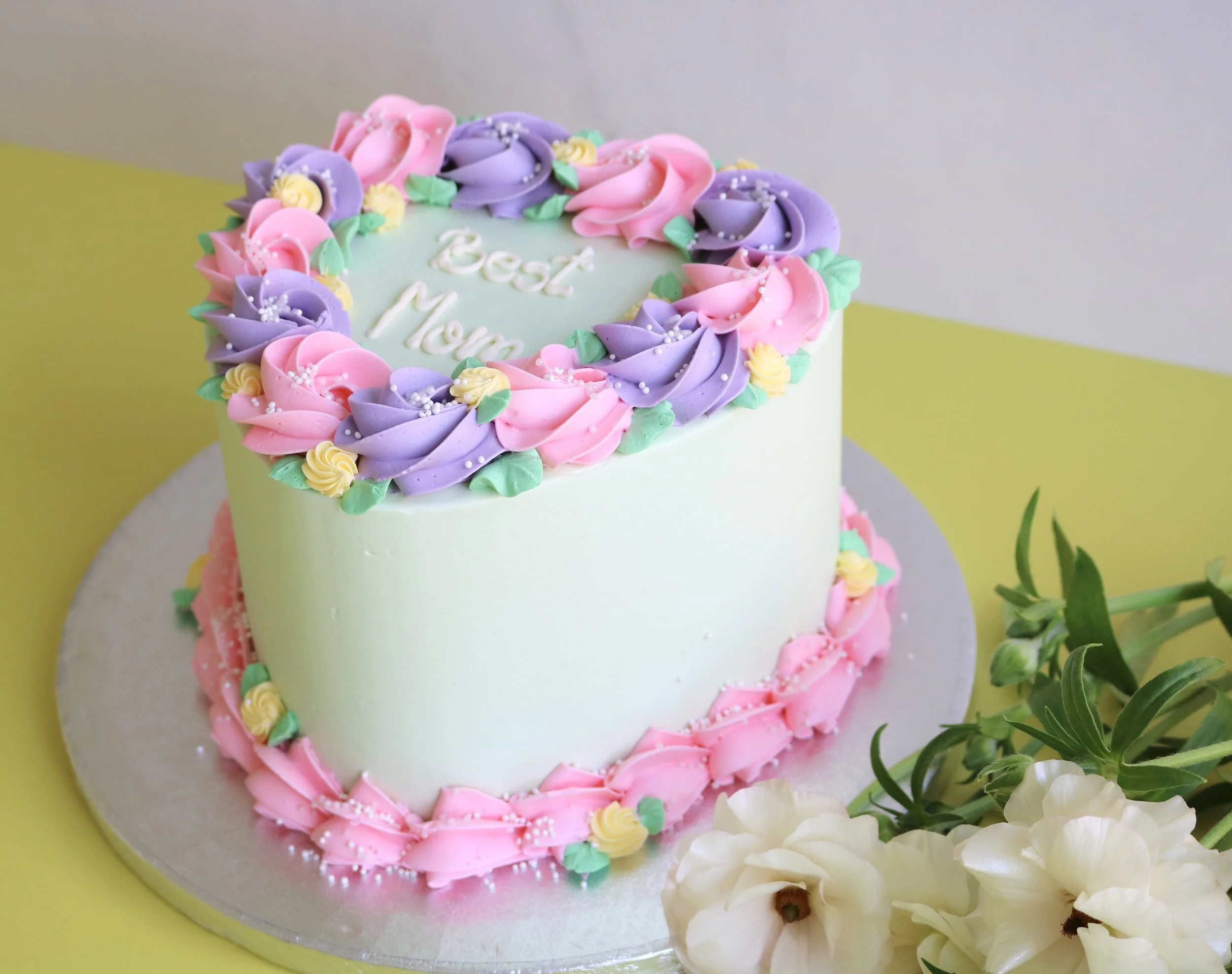 Heart-shaped Mother’s Day buttercream cake with pink and purple piped roses and pearl sprinkles by EM Cakes in London