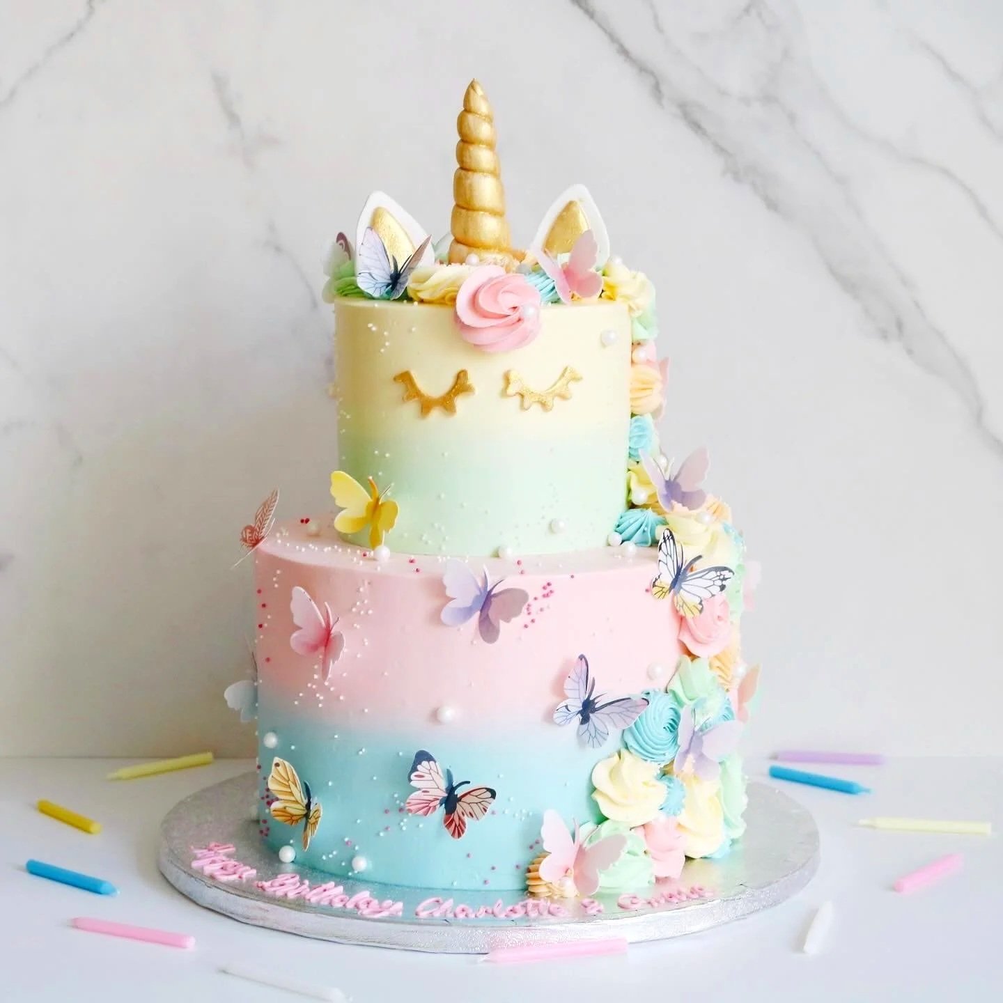 A jungle-themed birthday cake decorated with animals, leaves, and a 'Home' cake topper, with balloons in the background.