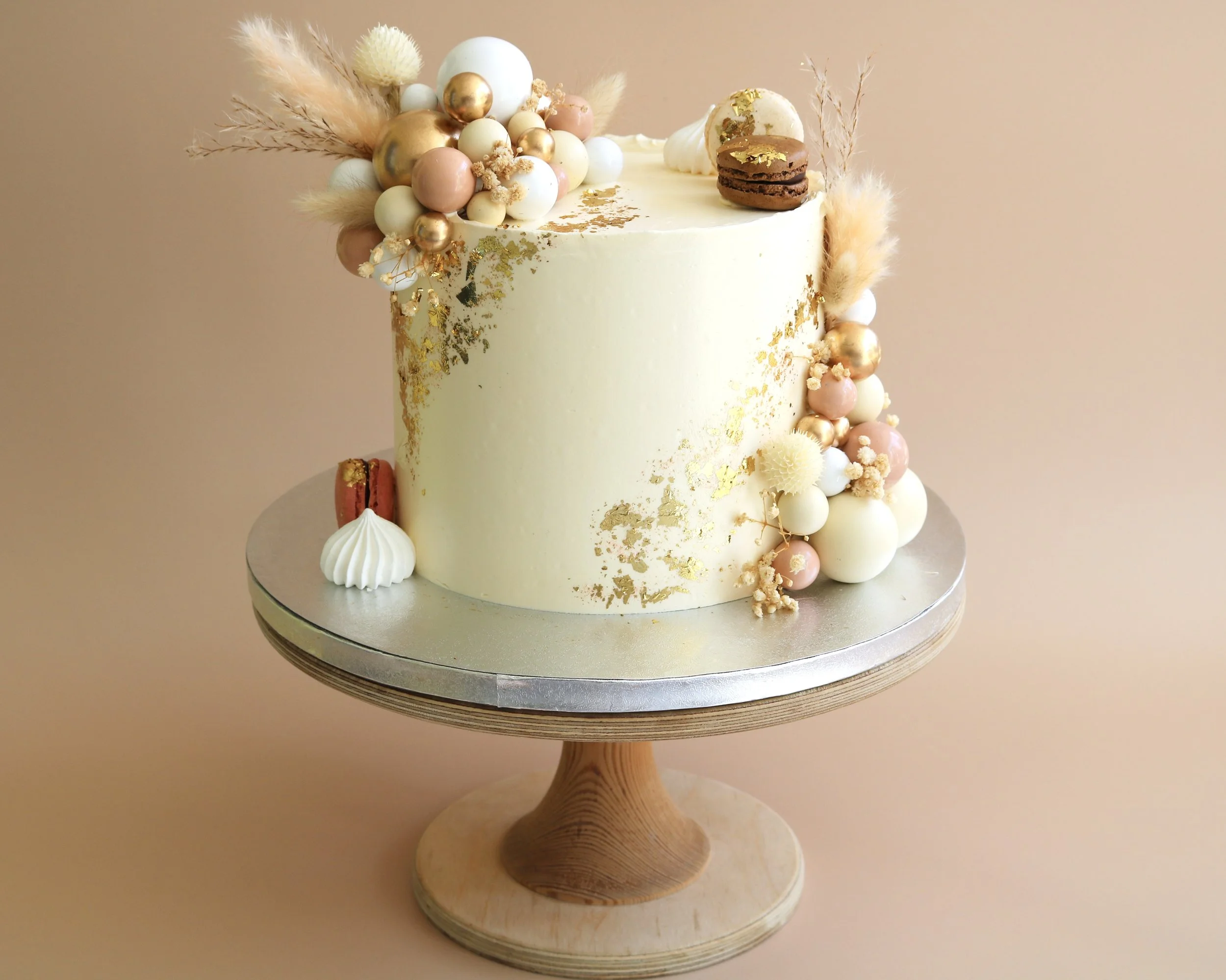 Luxury celebration cake with gold leaf, balloon decorations, macarons and dried flowers