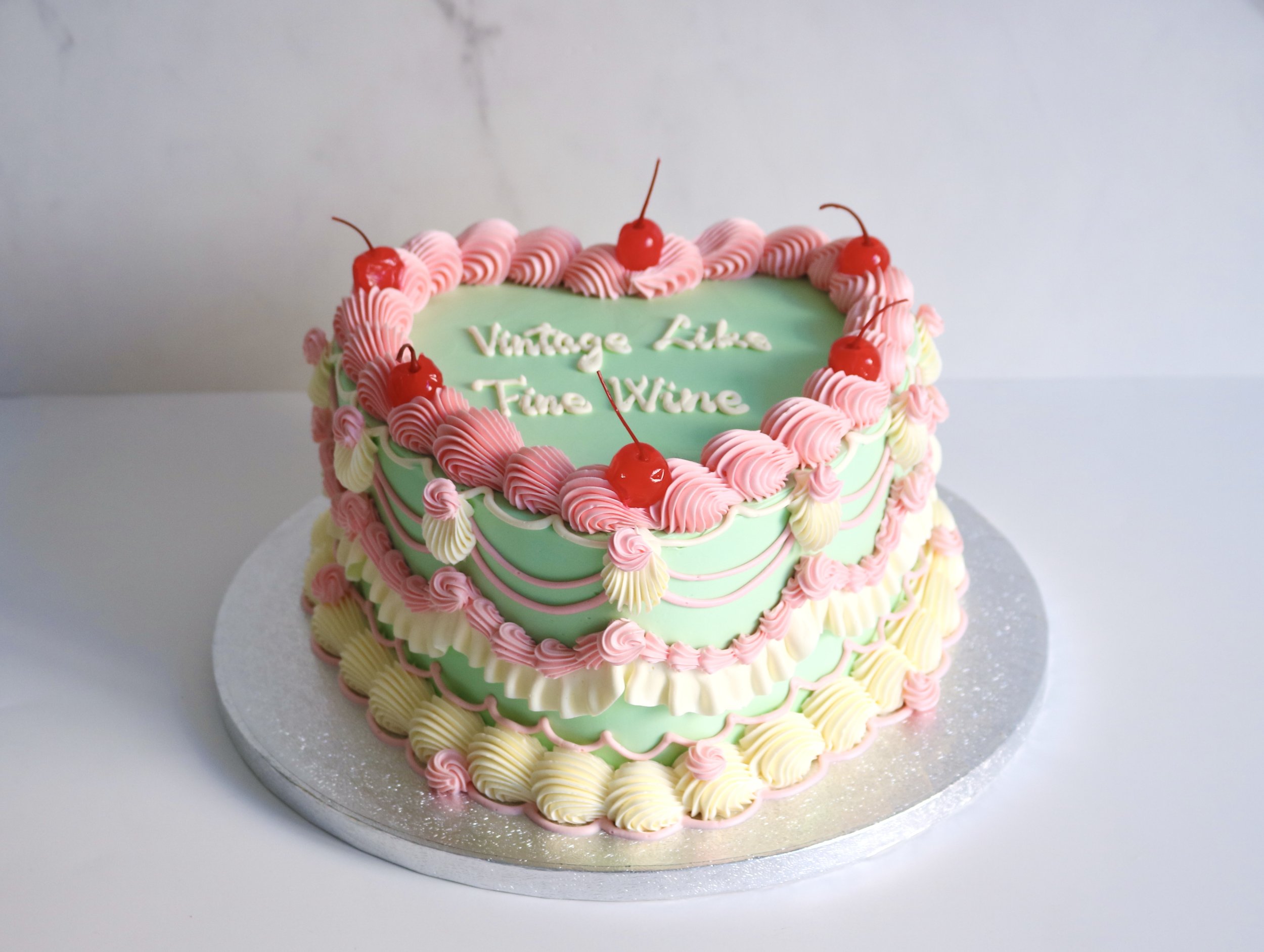 Luxury heart retro vintage cake in green and pink colour theme, with custom cake message and cocktail cherries toppings.