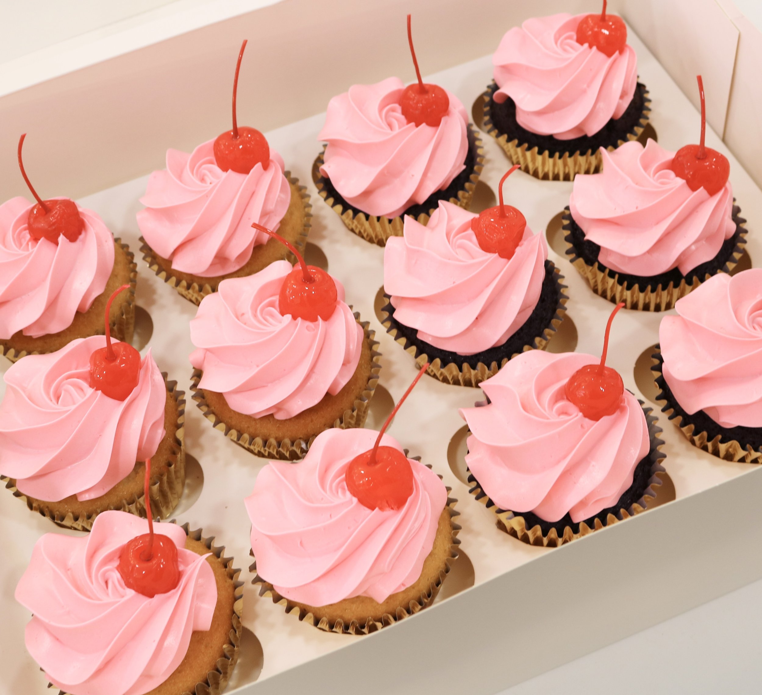 cupcakes with pastel colours and red maraschino cherries topper.