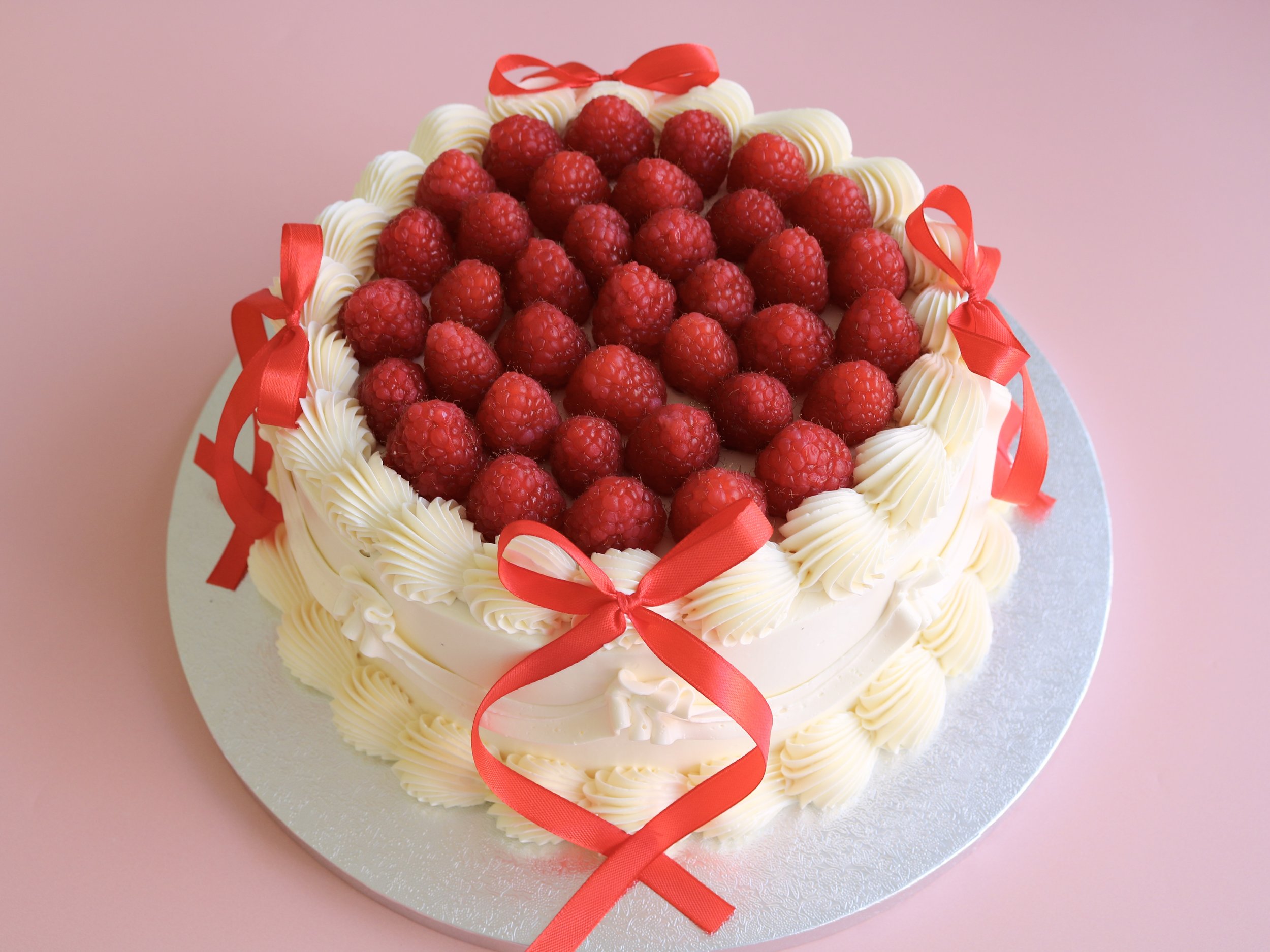 Raspberry bow vintage cake with fresh raspberries and red ribbon bows handmade in London