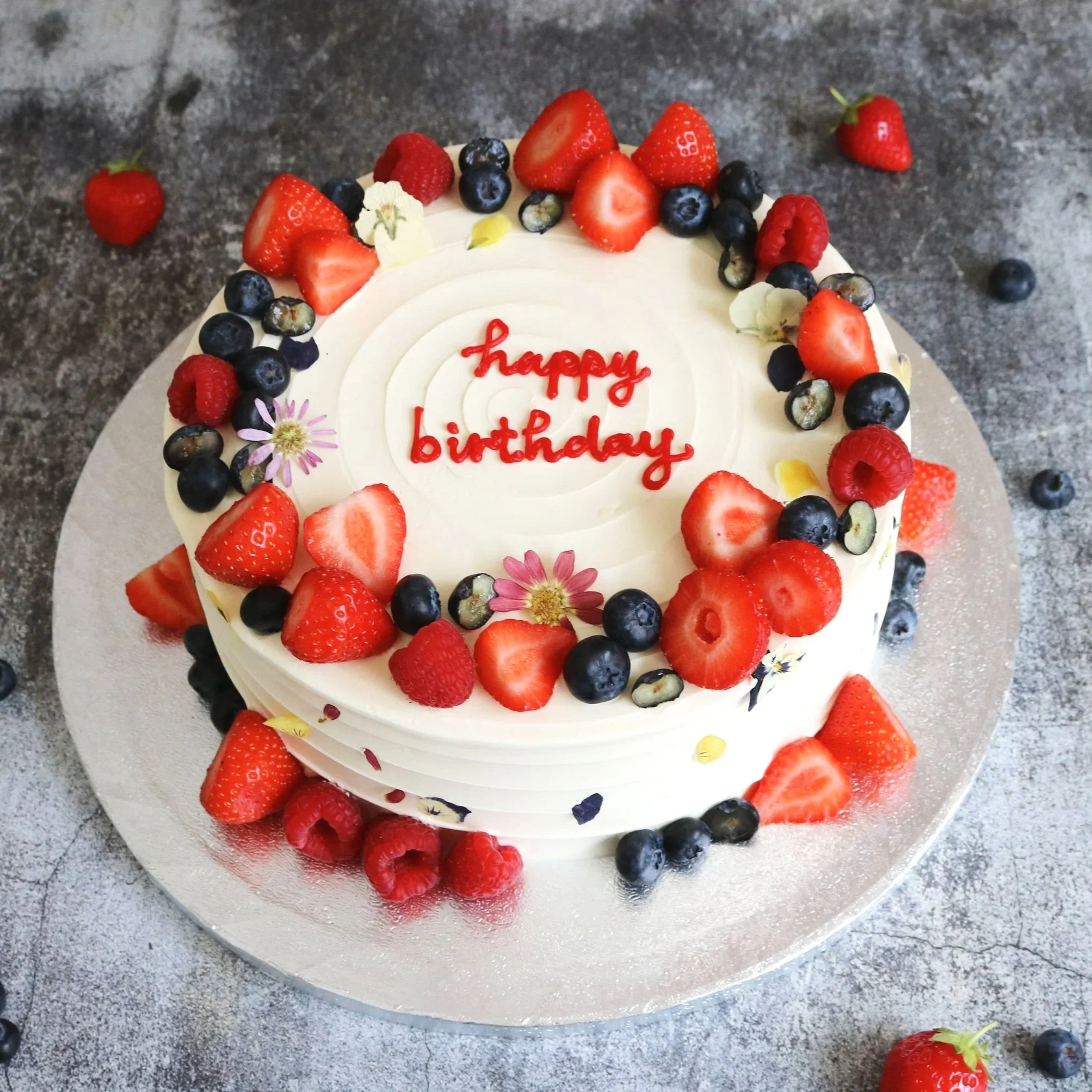 A  birthday cake with fresh fruits, and edible flowers decorations