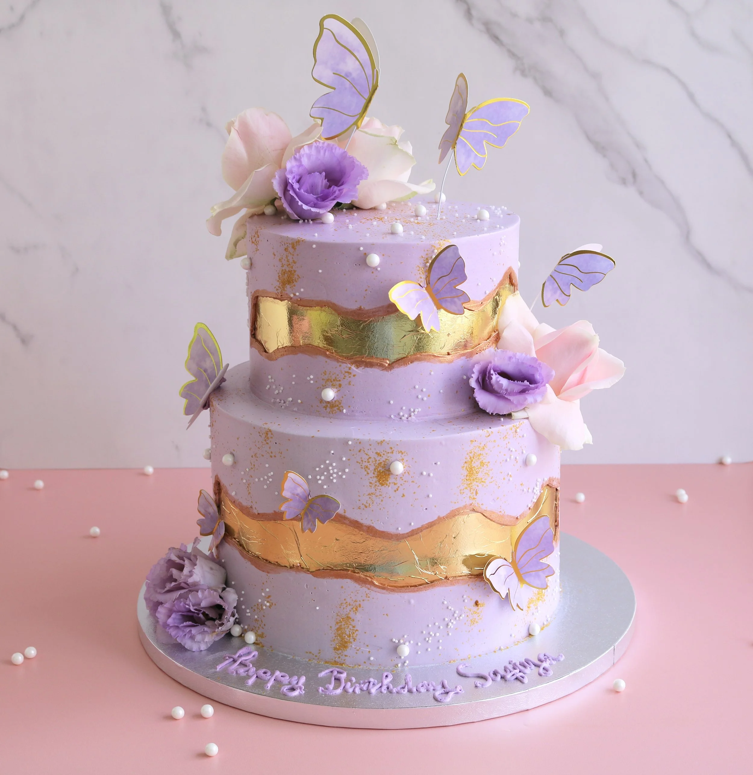 Luxury lilac fairy butterfly birthday cake with edible butterflies, gold fault line and fresh flowers in London.