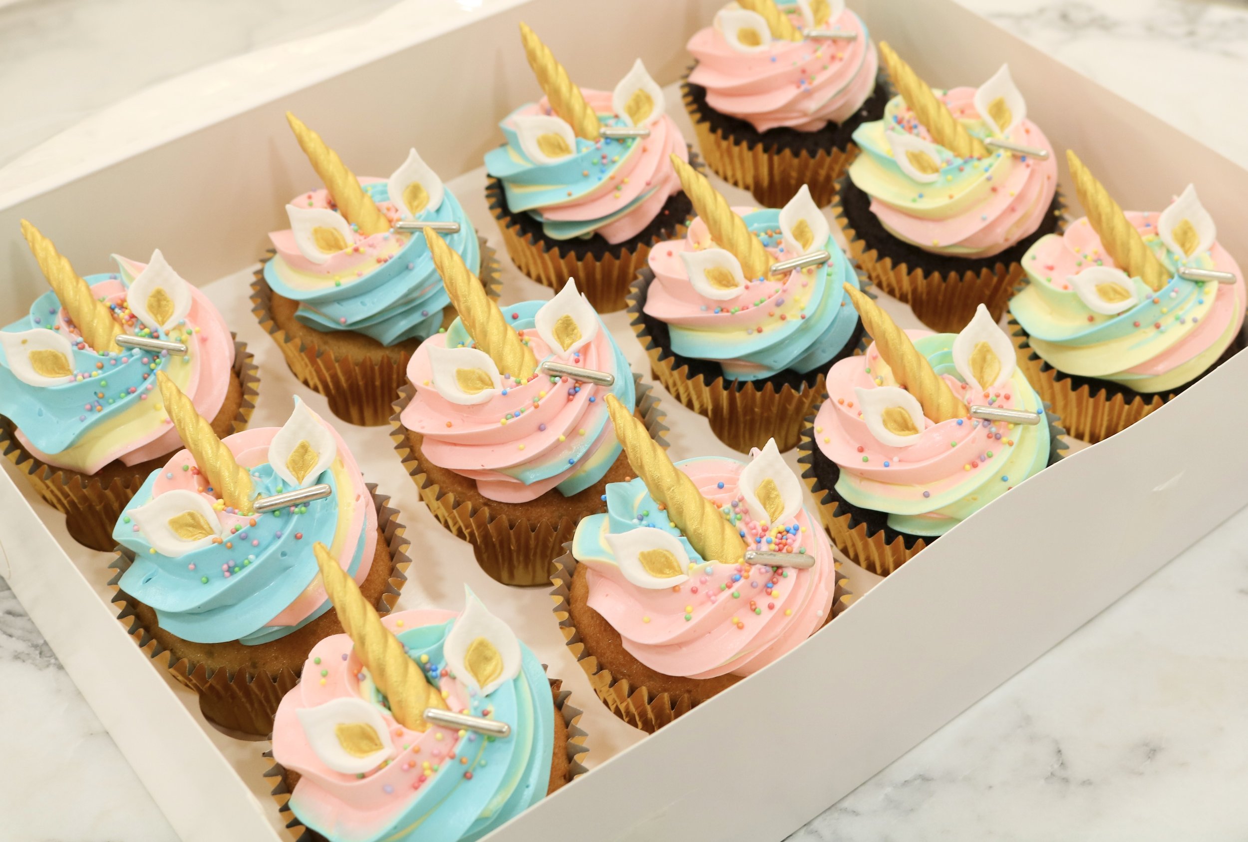 Unicorn cupcakes box in rainbow buttercream frosting and sprinkles for kids birthdays parties in London