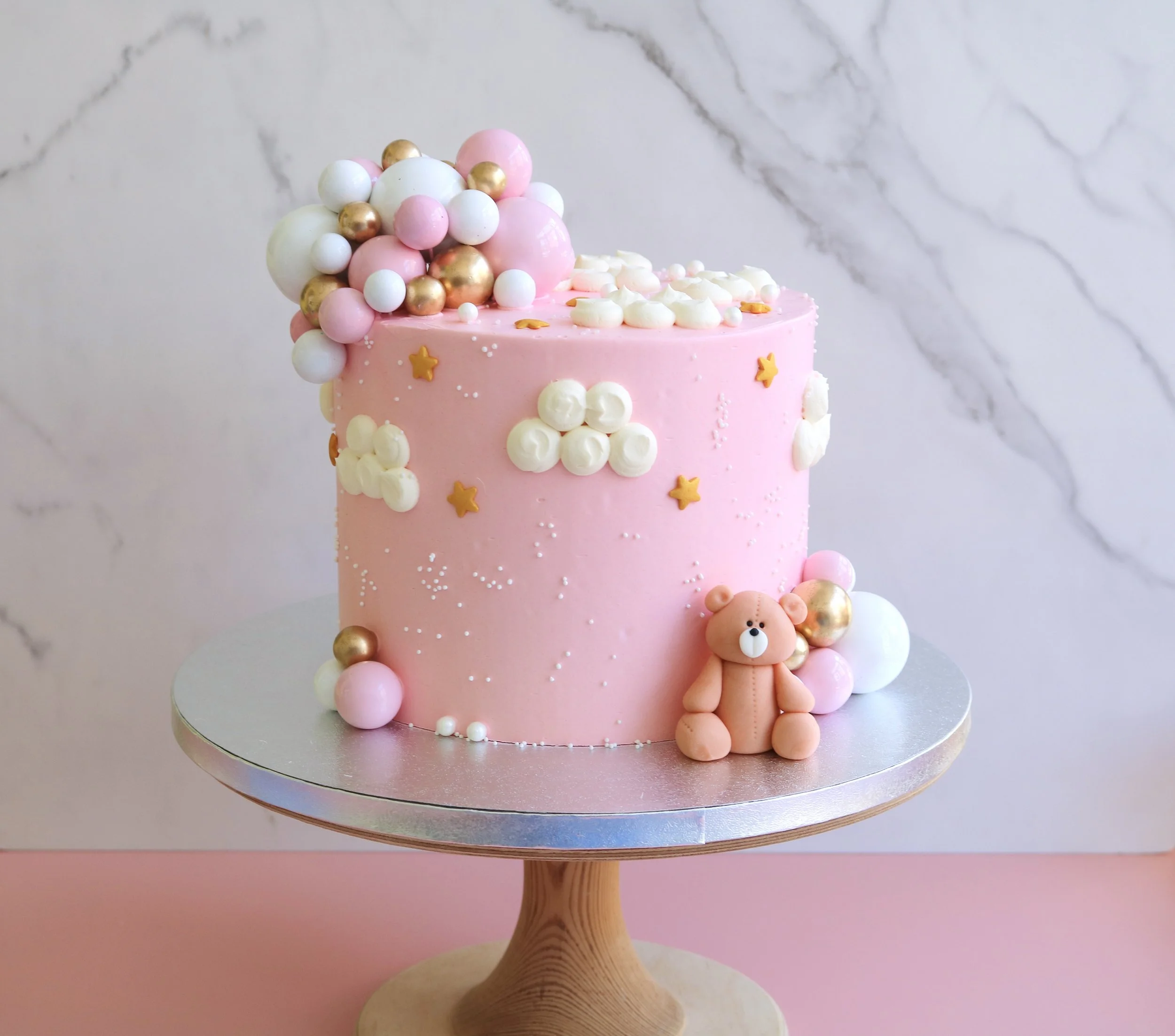 teddy bear birthday cake in light pink, clouds and stars, with handmade teddy bear