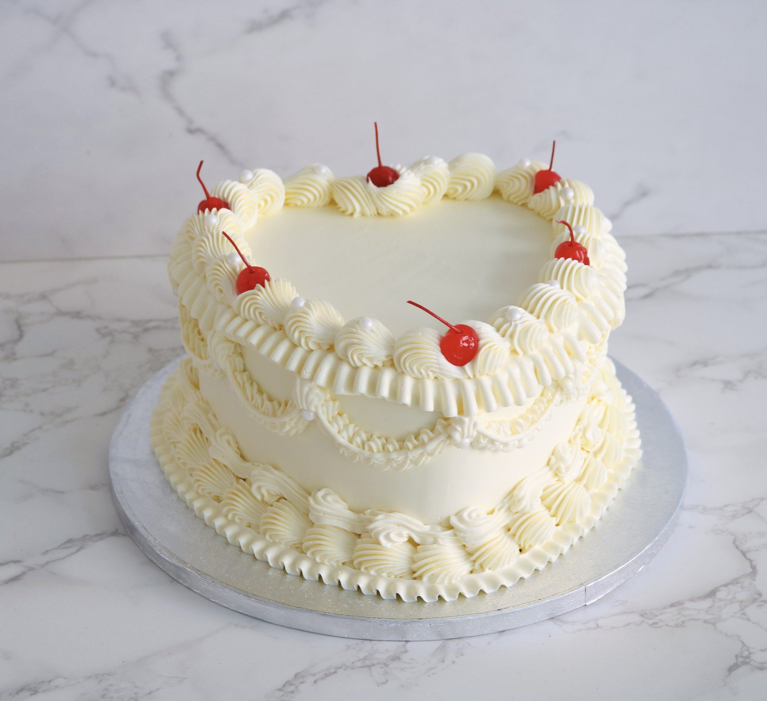 heart shaped vintage cake in all cream colour scheme with cherries on top