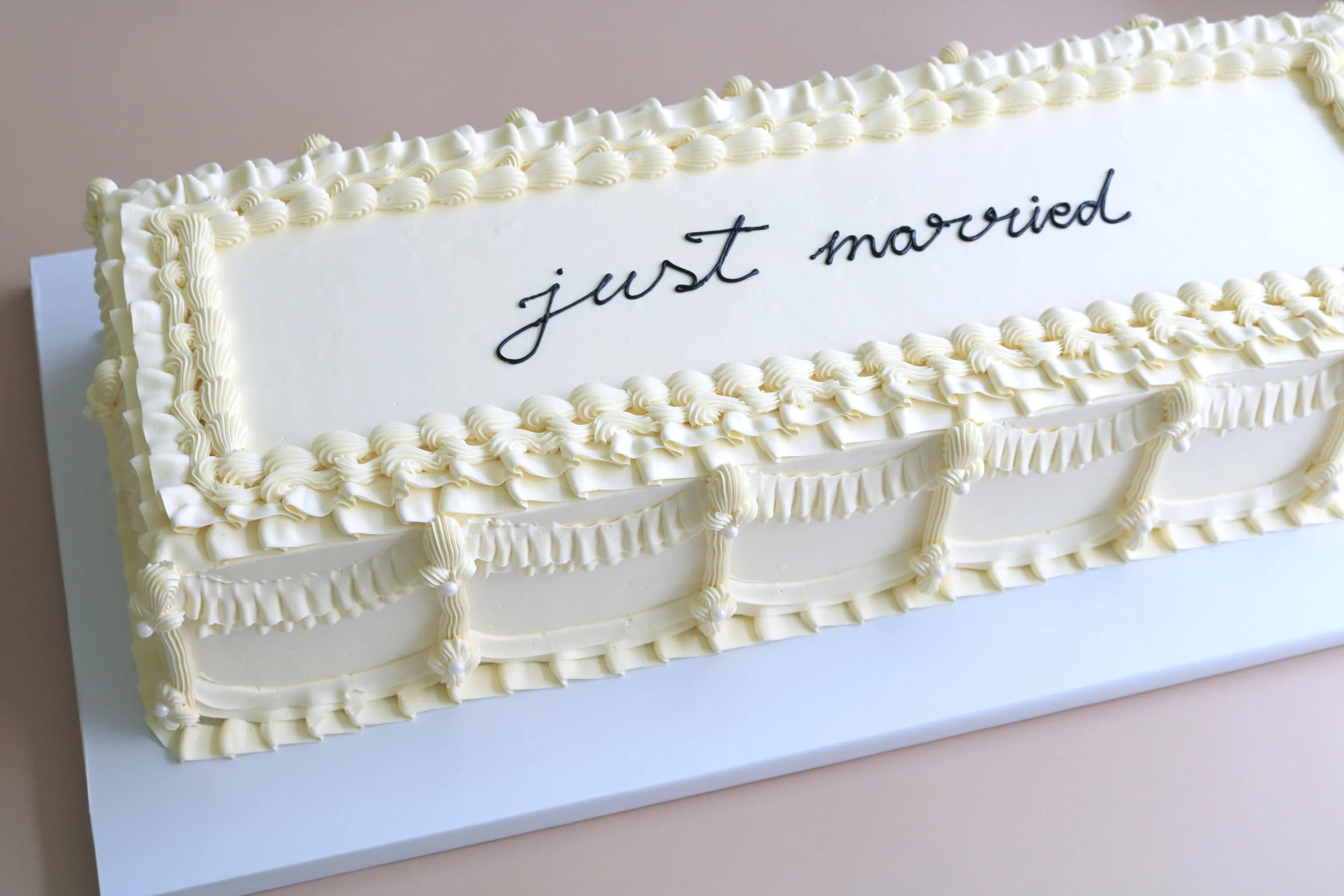 Extra-long rectangular wedding cake with vintage buttercream piping and just married message