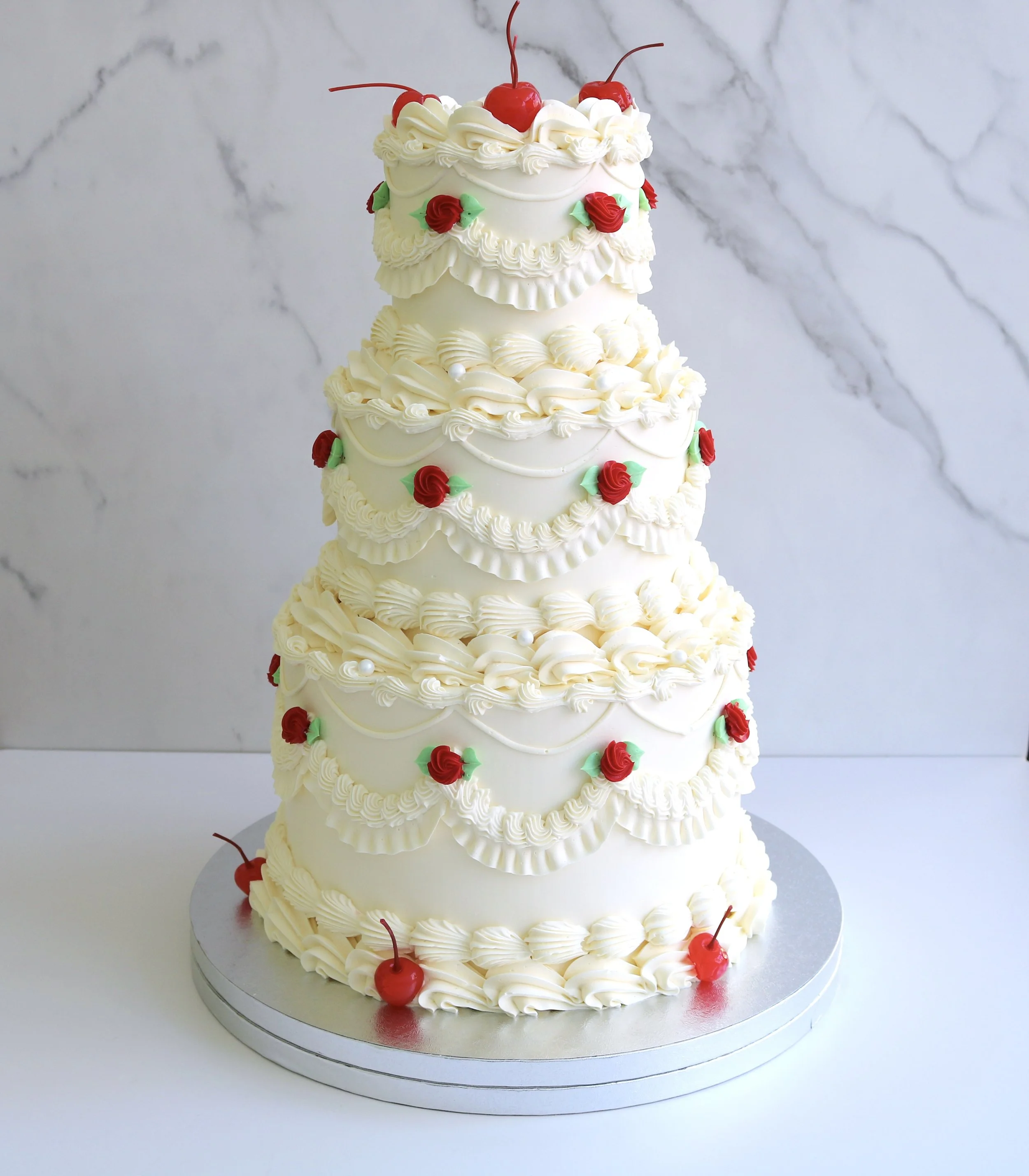 Tiered vintage Lambeth wedding cake with cream buttercream piping, red roses and maraschino cherries