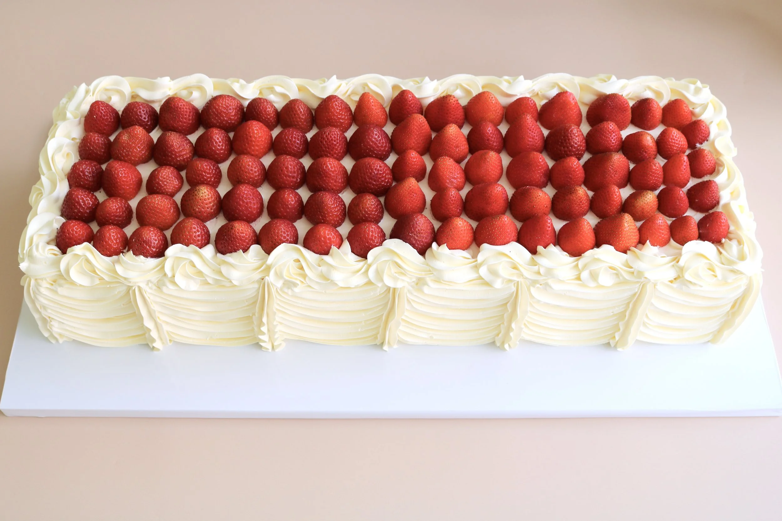 Extra-long rectangular wedding cake with fresh strawberries and vintage buttercream piping