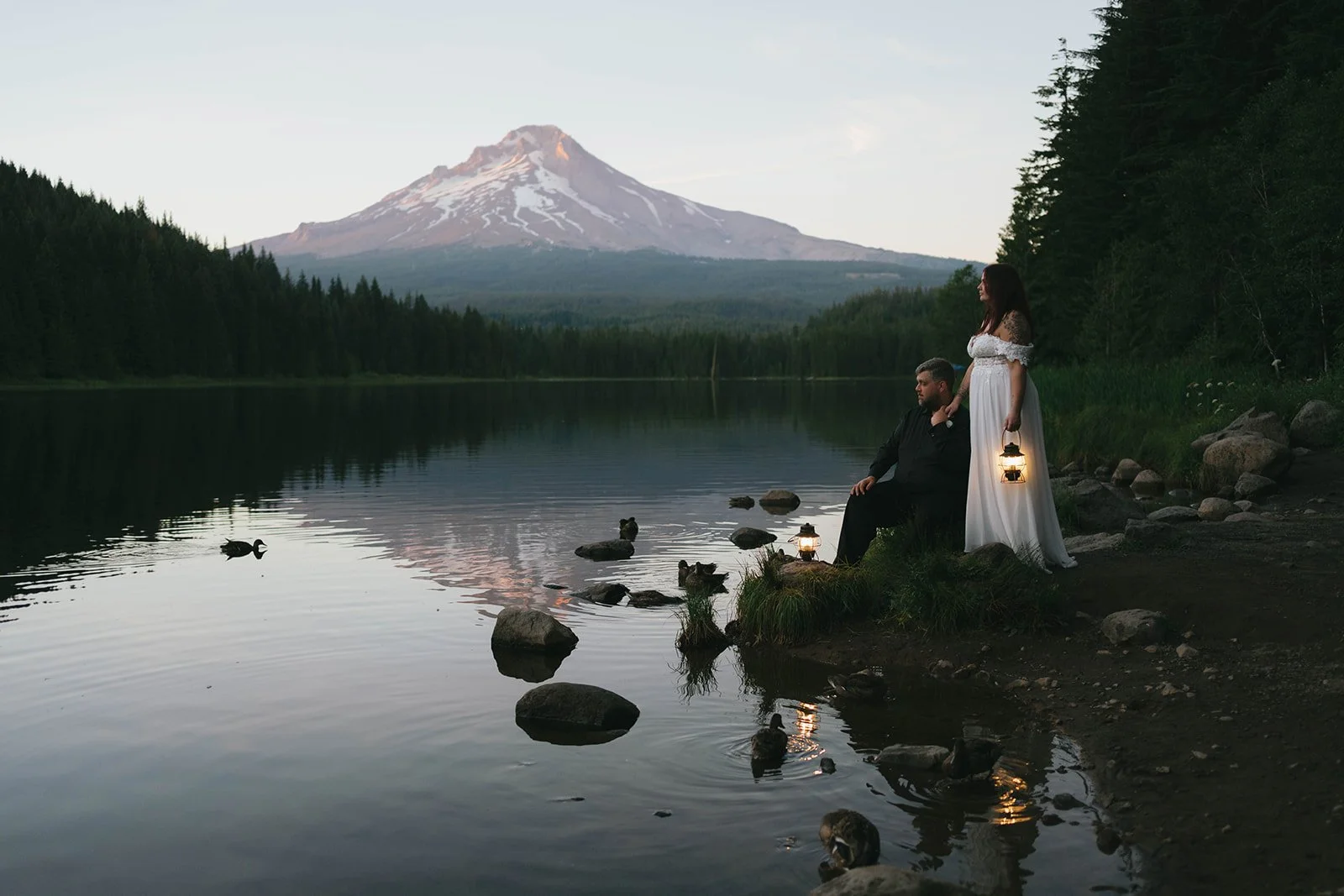 Couple holding lanterns at sunset at Trillium Lake in Oregon during their elopement