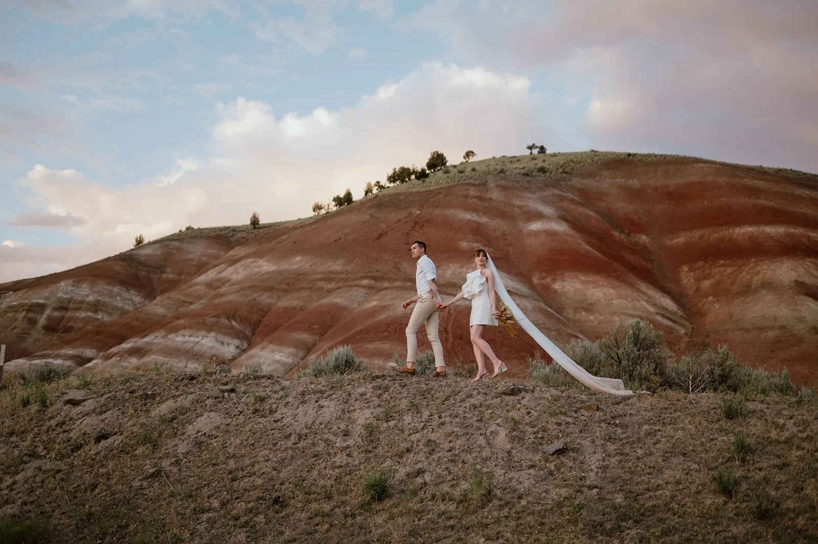 husband and wife walking at sunset during their elopement at the Painted Hills in Oregon