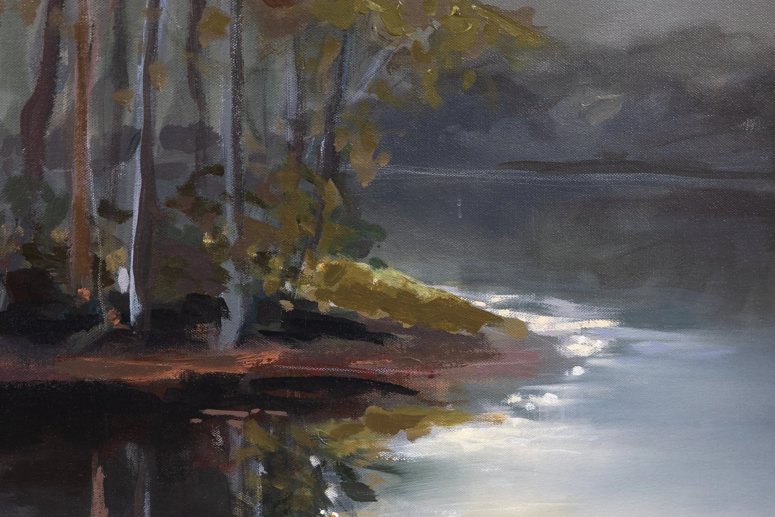 Close-up of The First Glimpse of Light showing dark woodland trees, warm shoreline colors, and golden morning light reflecting across the water.
