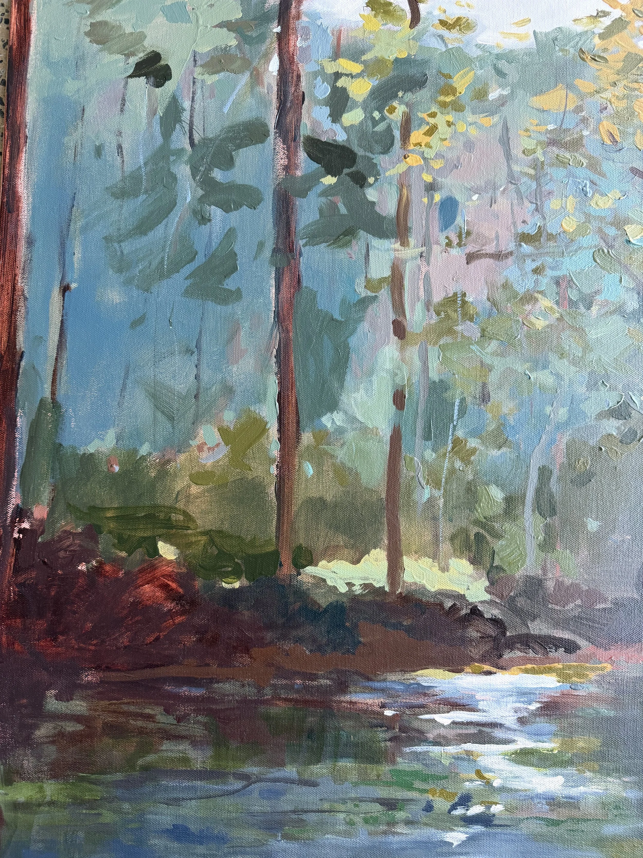 Detail of quiet water leading toward a layered forest illuminated by soft green and golden light.