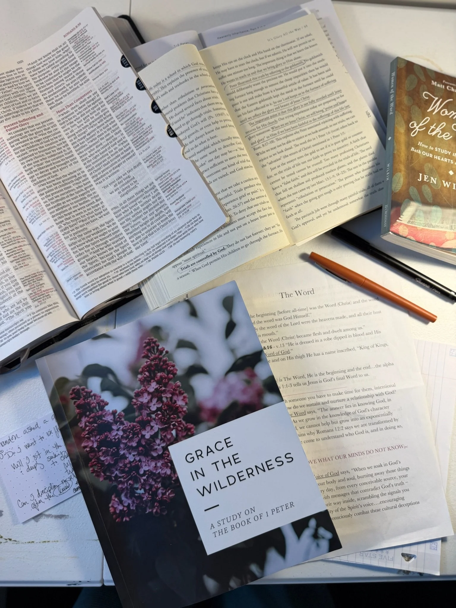 Bible study materials, open books, handwritten notes, and a printed study titled “The Word” arranged on a desk.